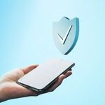 A phone being held with a checkmark hovering above it.