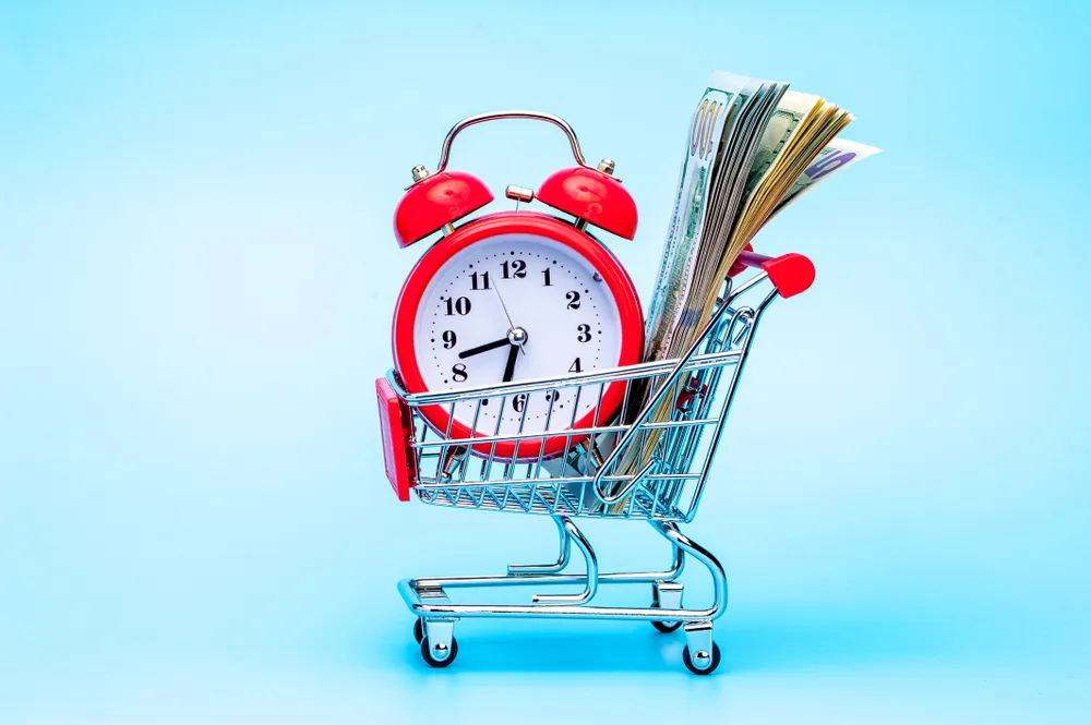Red Retro Alarm Clock And Dollar Bills In Shopping Cart