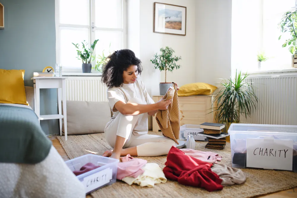 Young Woman Sorting Wardrobe Indoors At Home Charity Donation Concept.