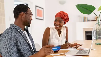 Mature Smiling Couple Sitting And Managing Expenses At Home. Happy