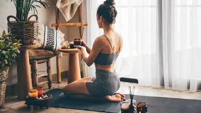 Young Relaxed Woman Doing Yoga At Home With Candles And
