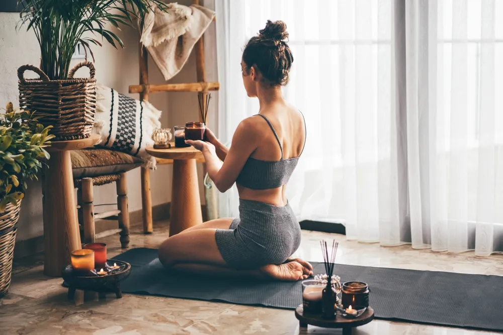Young Relaxed Woman Doing Yoga At Home With Candles And