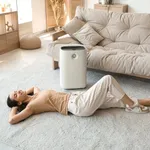 Young Woman Lying On Floor Near Humidifier In Beautiful Living
