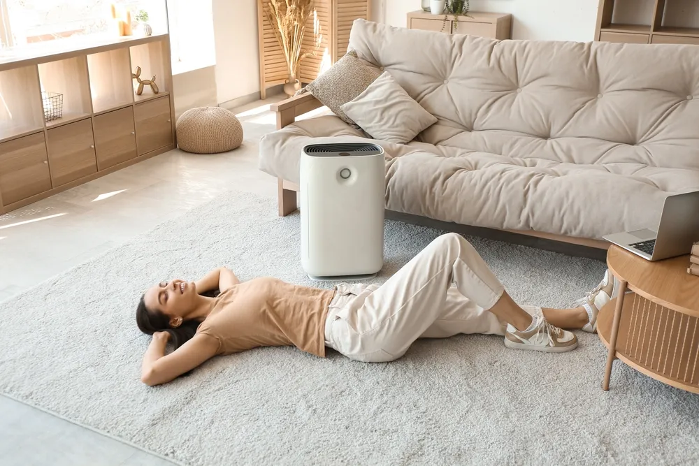 Young Woman Lying On Floor Near Humidifier In Beautiful Living