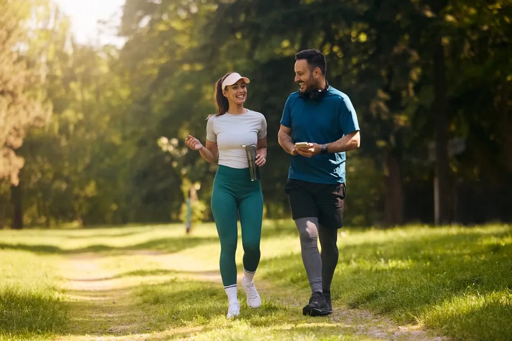 Happy Athletic Couple Communicating While Walking In Nature After Sports