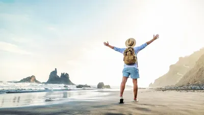 Happy Traveler With Hands Up Standing At The Beach -