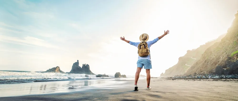 Happy Traveler With Hands Up Standing At The Beach -