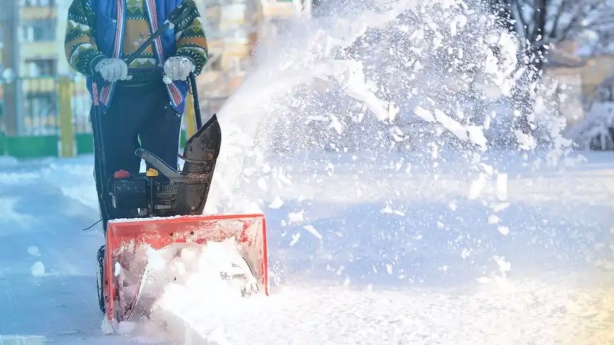 A person clearing snow off their driveway with a snowblower.