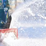 A person clearing snow off their driveway with a snowblower.